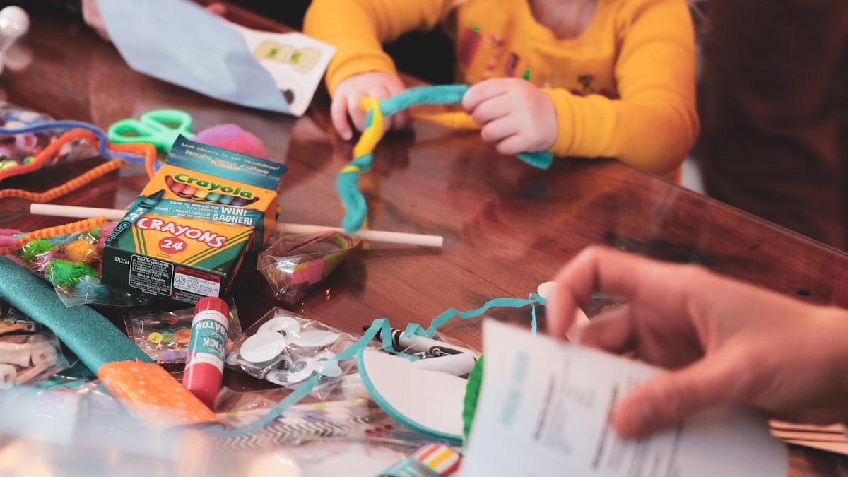 a young girl sitting at a table with lots of craft supplies